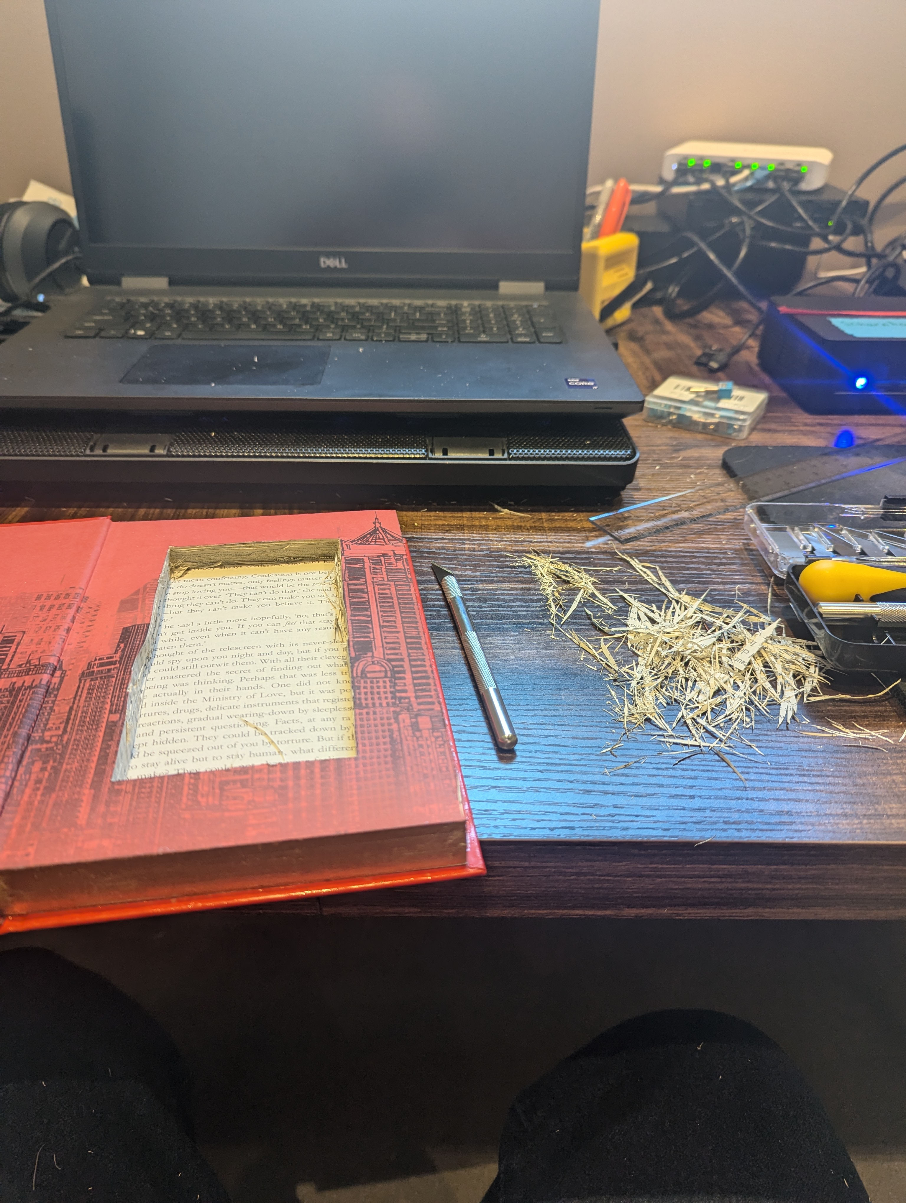 Cutting in progress — shredded paper on desk, blade and book visible